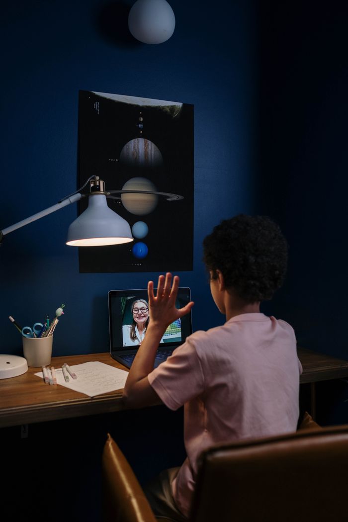 A child participates in an online class in a neatly arranged study room.